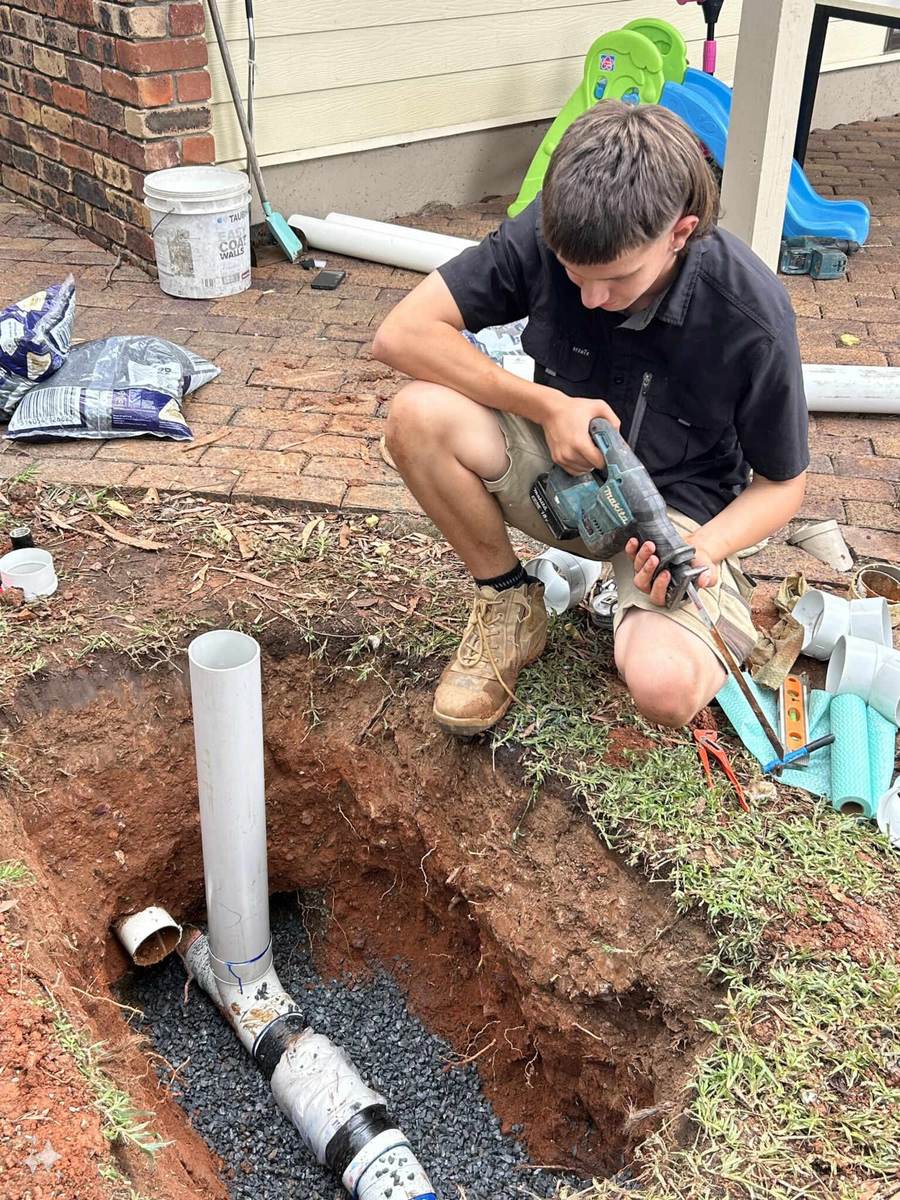 Brown Arm Boys plumber installing new drainage pipe